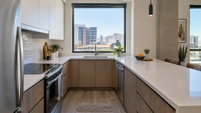 Compact modern condo kitchen in downtown Tempe, Arizona with flat-panel cabinets, quartz counters and a window looking out at mid-rise buildings