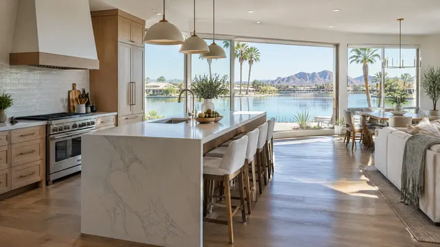 Remodeled open kitchen with an island facing large windows that look out over a calm lake and palm trees